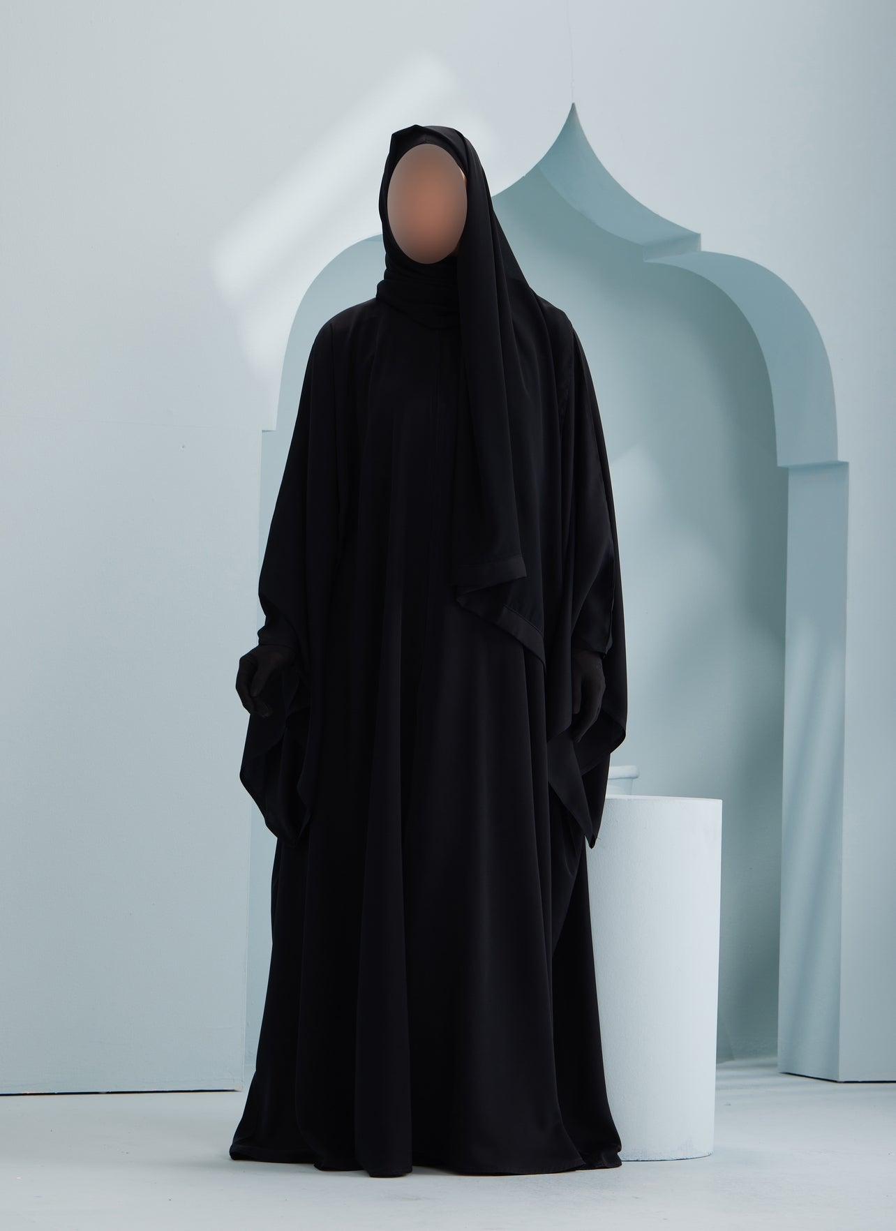 women wearing traditional black abaya with a matching chiffon scarf on aqua background