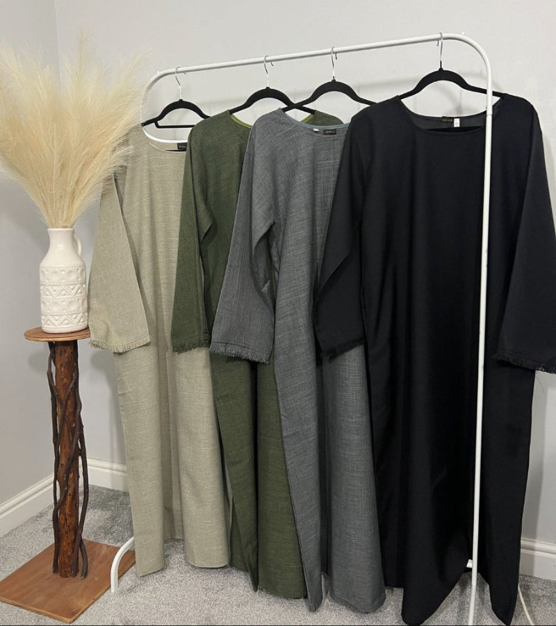 4 linen abayas with pockets hung up on clothing rail in corner of a room