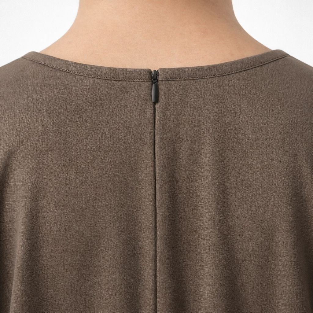 Close-up of a taupe abaya with a zipper detail on a white background